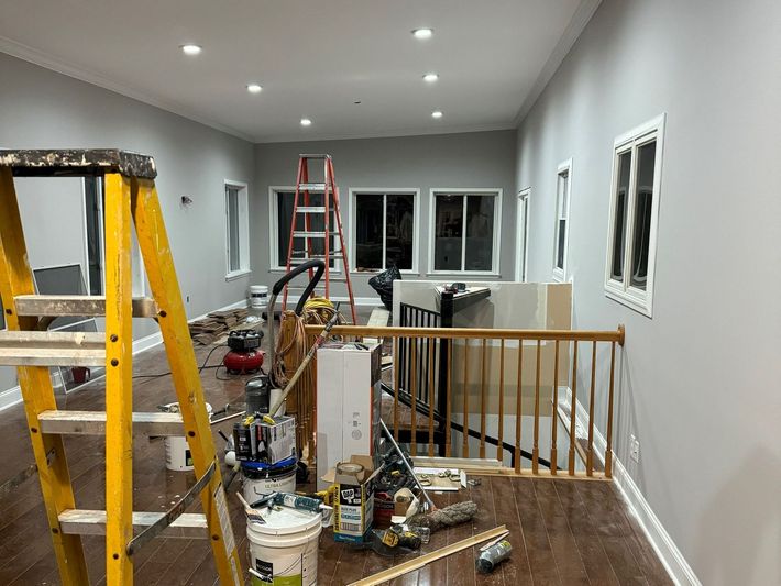 A room with a ladder and buckets of paint in it is being painted.