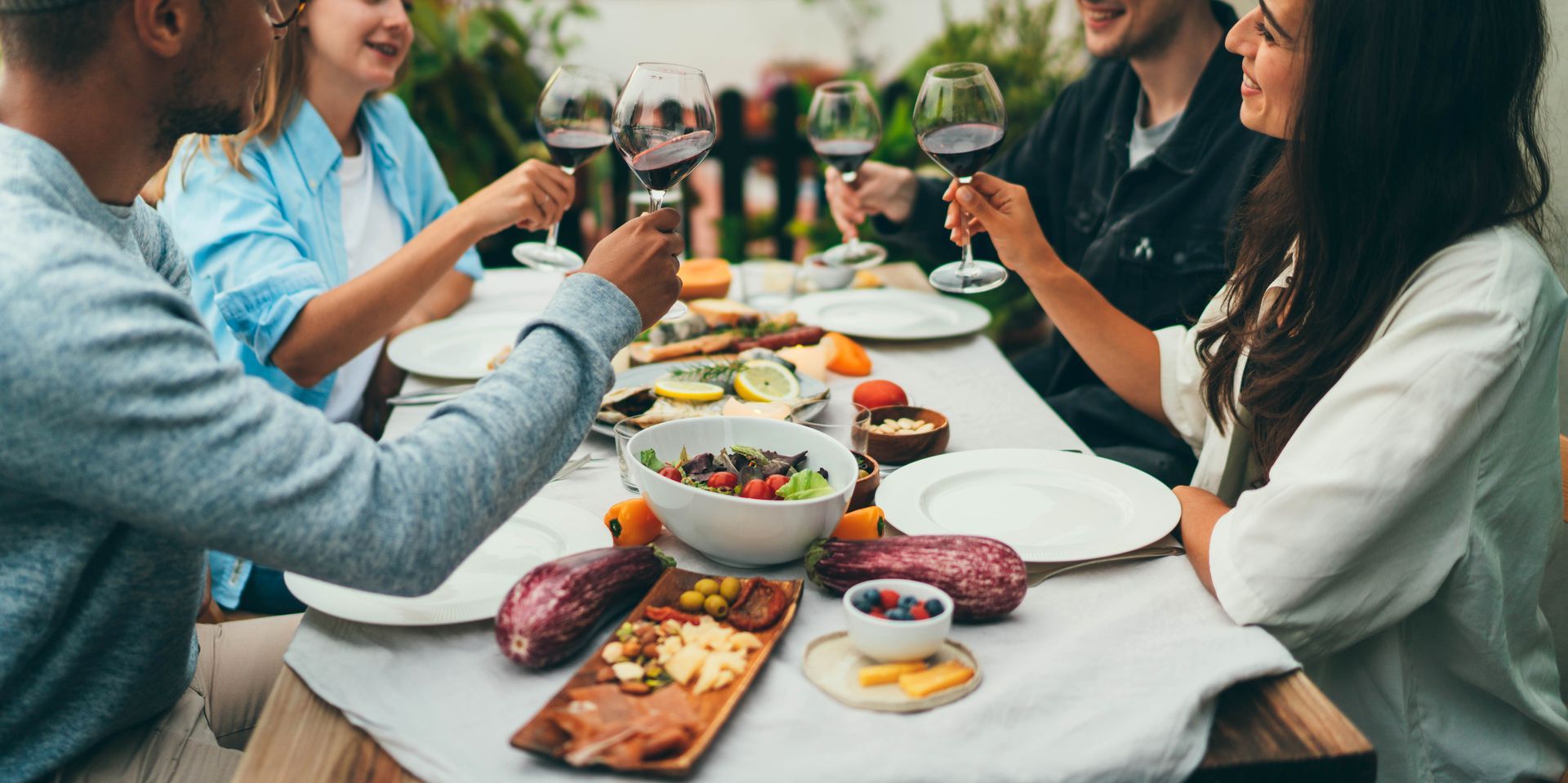 People toasting with wine glasses at a table set for a meal.