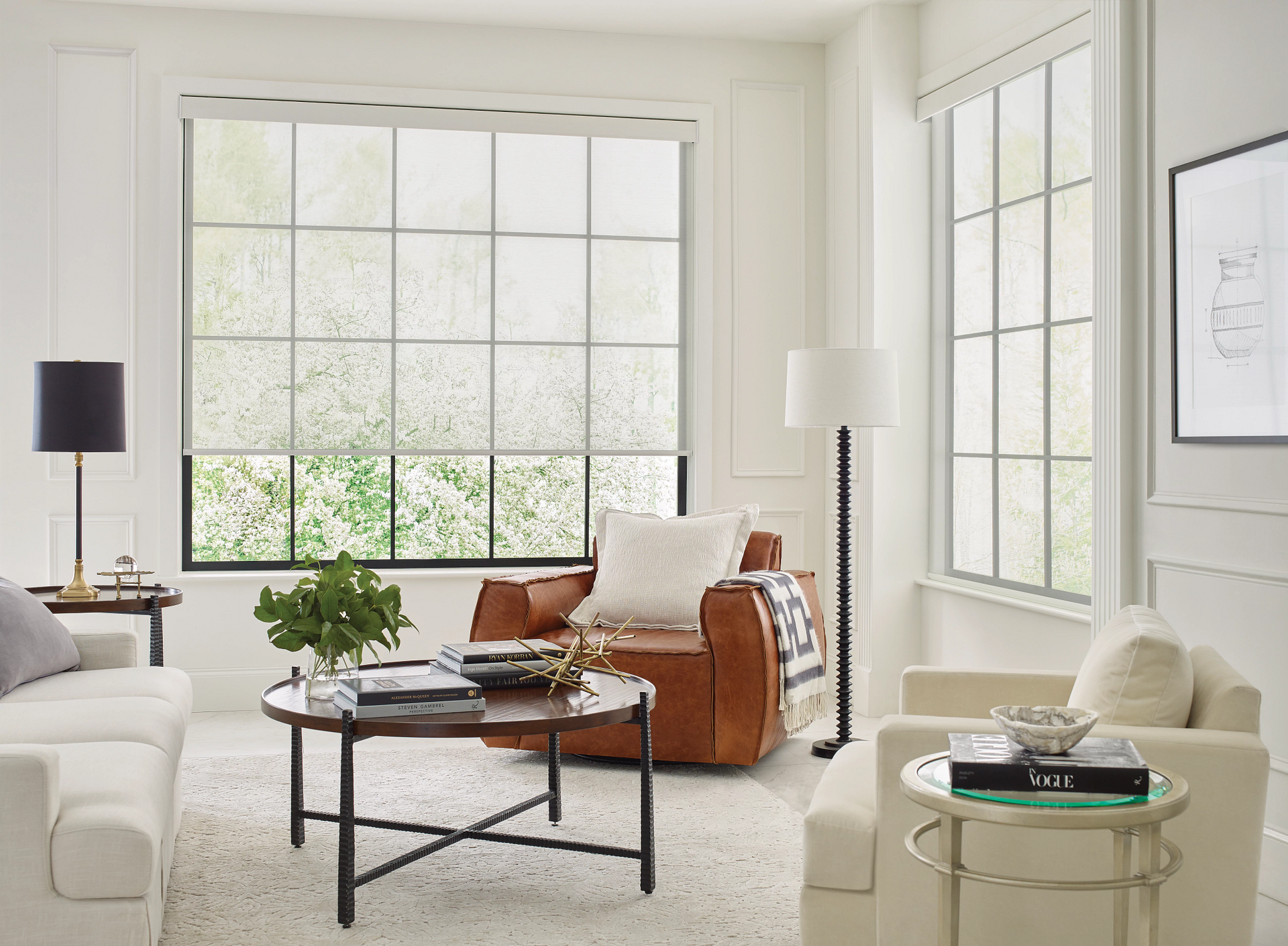 Bright living room with large windows, cream furniture, a leather chair, and a glass coffee table.