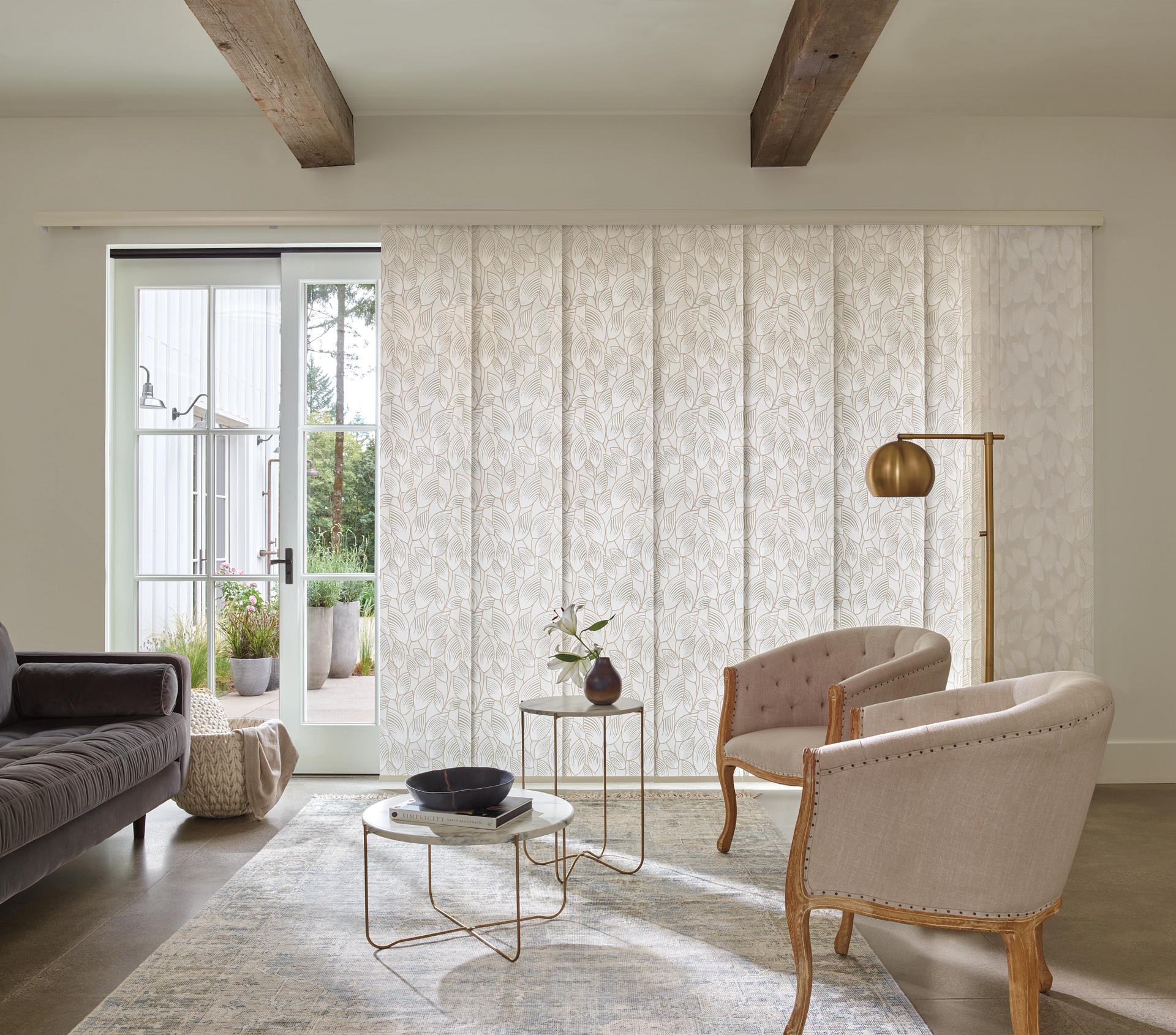 Bright living room with sheer curtains, beige chairs, coffee table, rug, sofa, and floor lamp by a window.