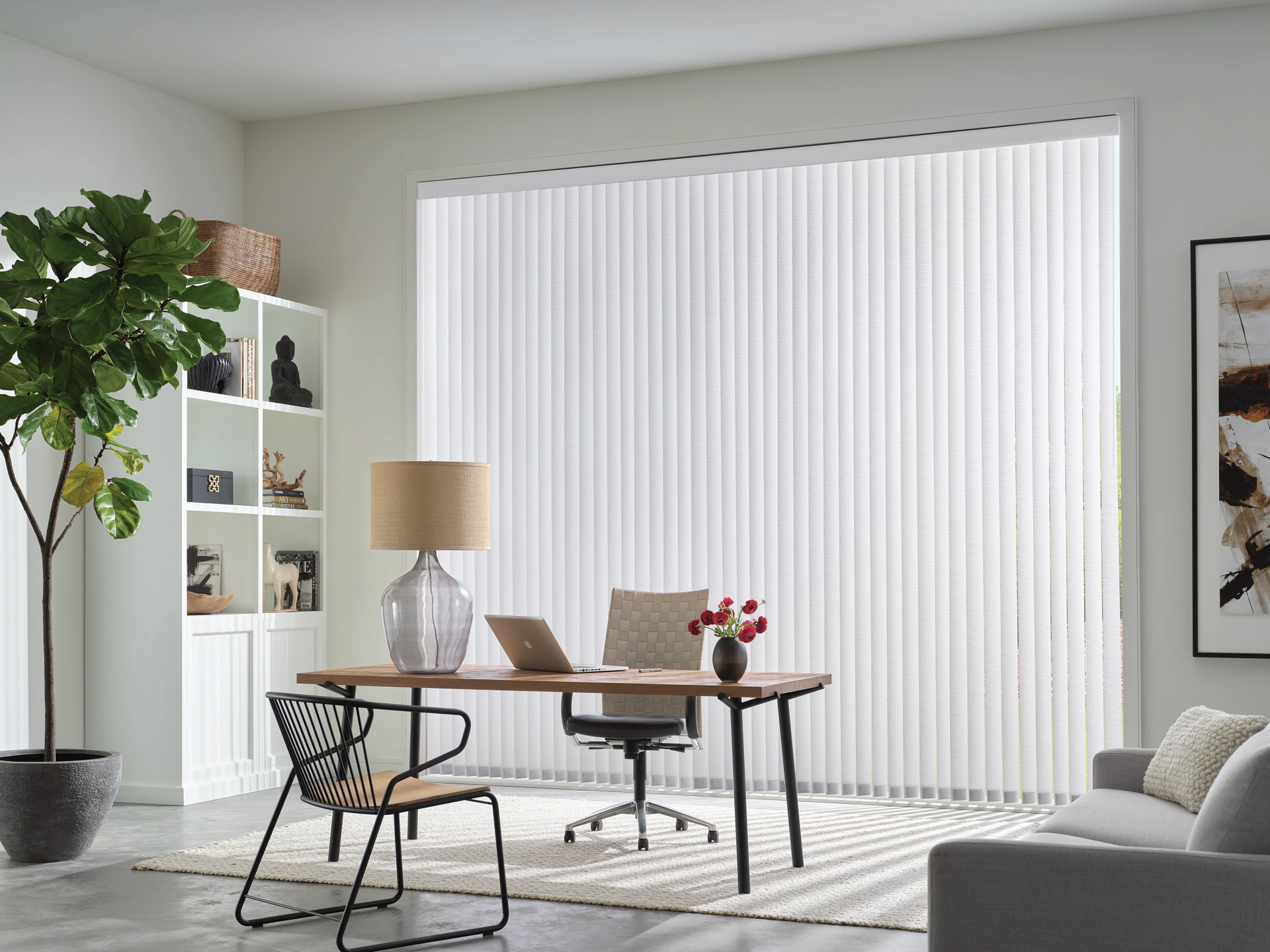 Modern home office with desk, chair, lamp, plants, and vertical blinds in a bright room