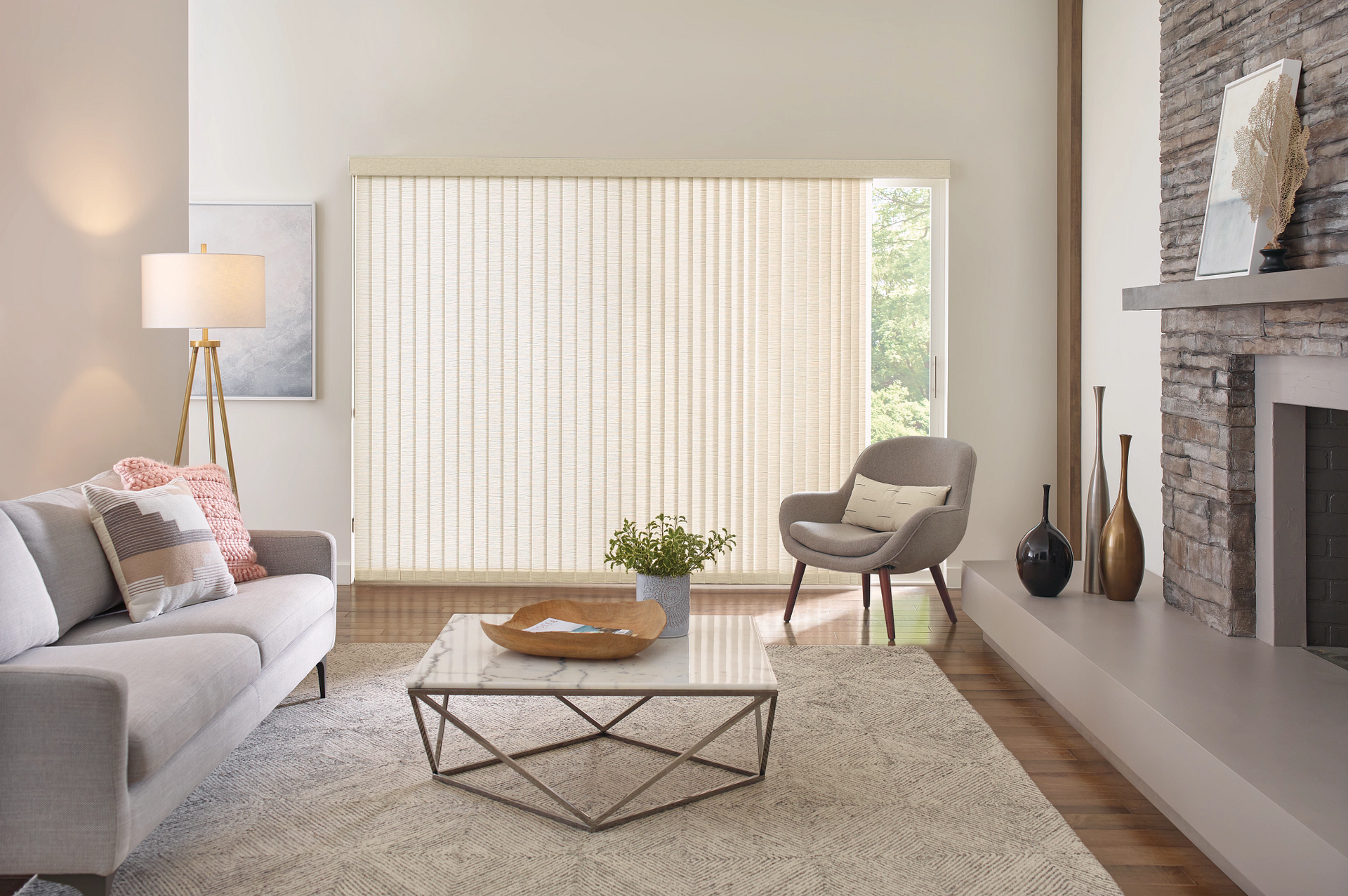 Modern living room with gray sofa, round chair, coffee table, large window blinds, and stone fireplace