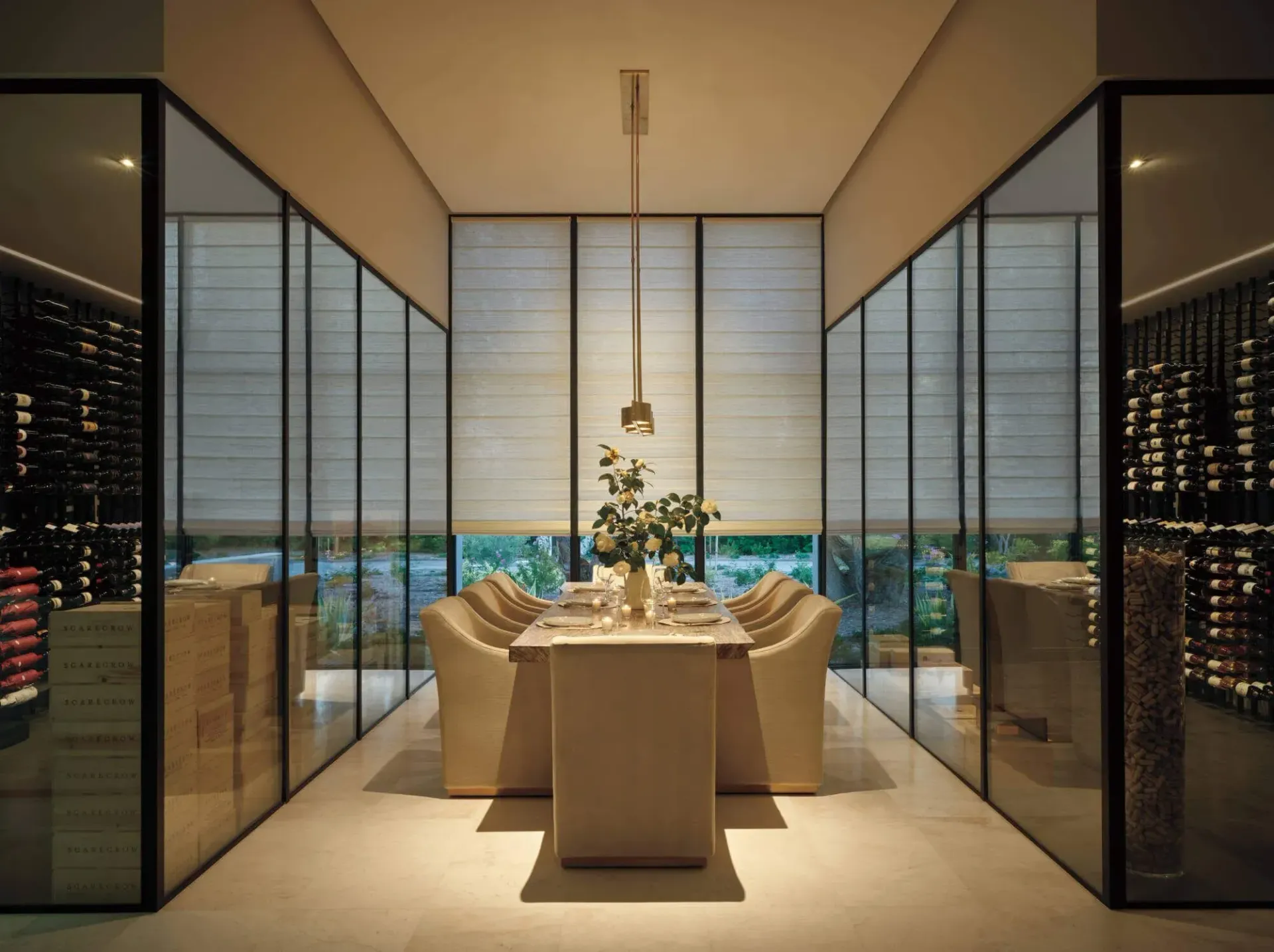 Elegant dining room with a long set table, floor-to-ceiling windows, and city views at night