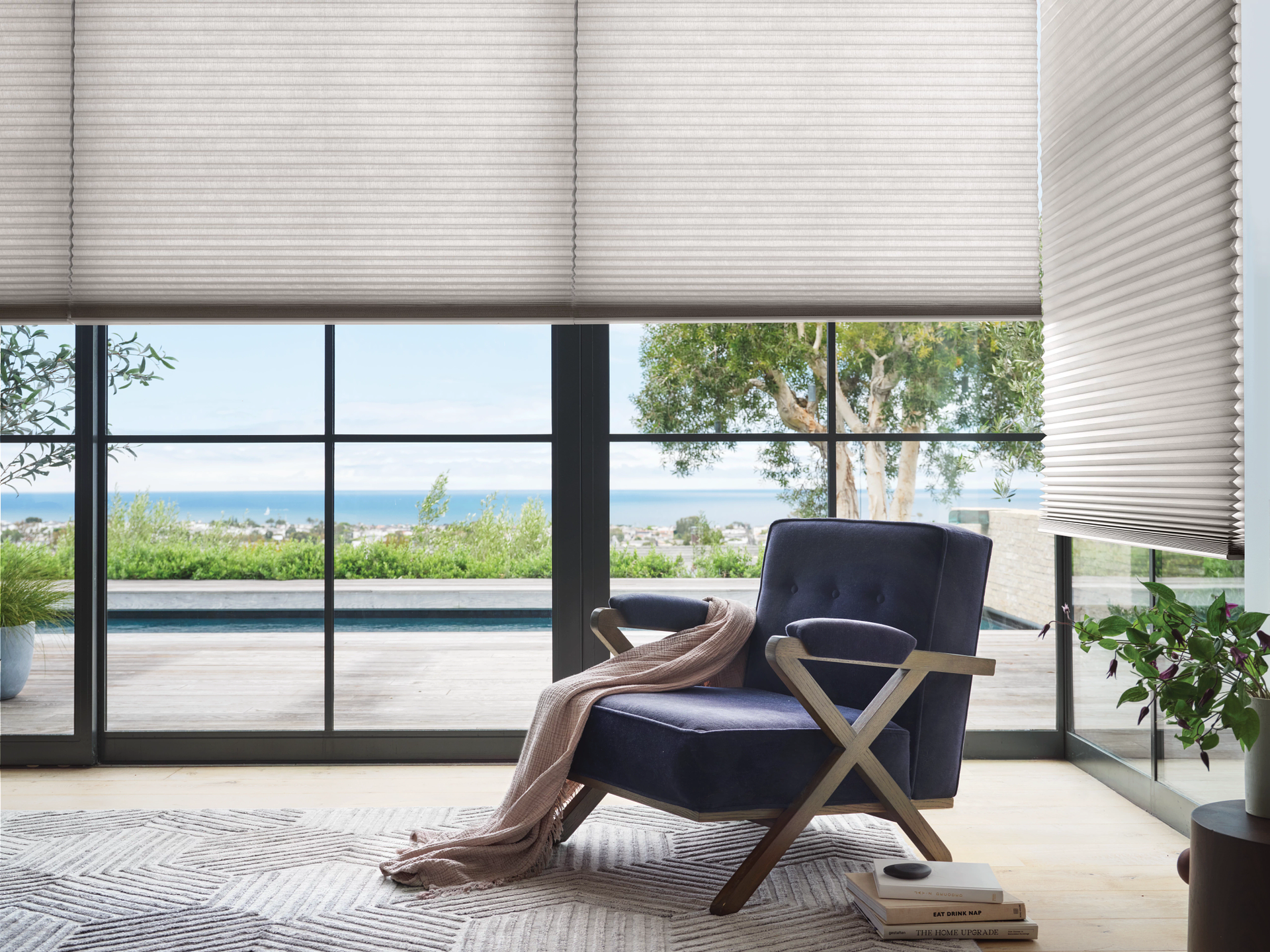 Modern living room with navy chair, throw blanket, and ocean view through large windows