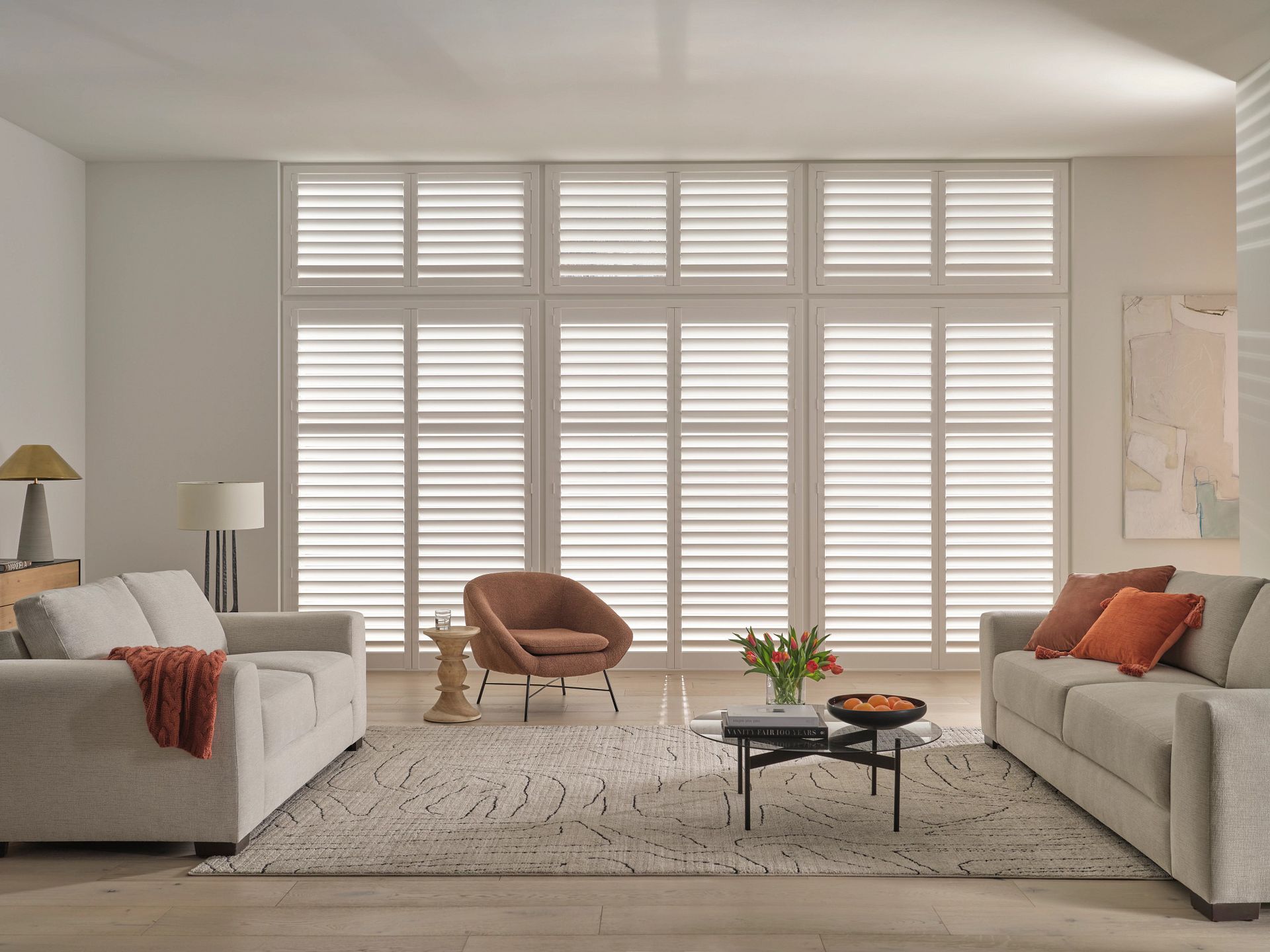 Bright living room with two sofas, a chair, coffee table, and large window shutters