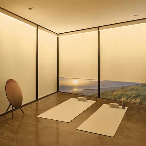 Minimalist tatami room with warm lighting, two floor mats, and a low window overlooking a sunset landscape