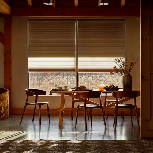 Cozy dining room with a wooden table, four chairs, and sunlight filtering through window blinds
