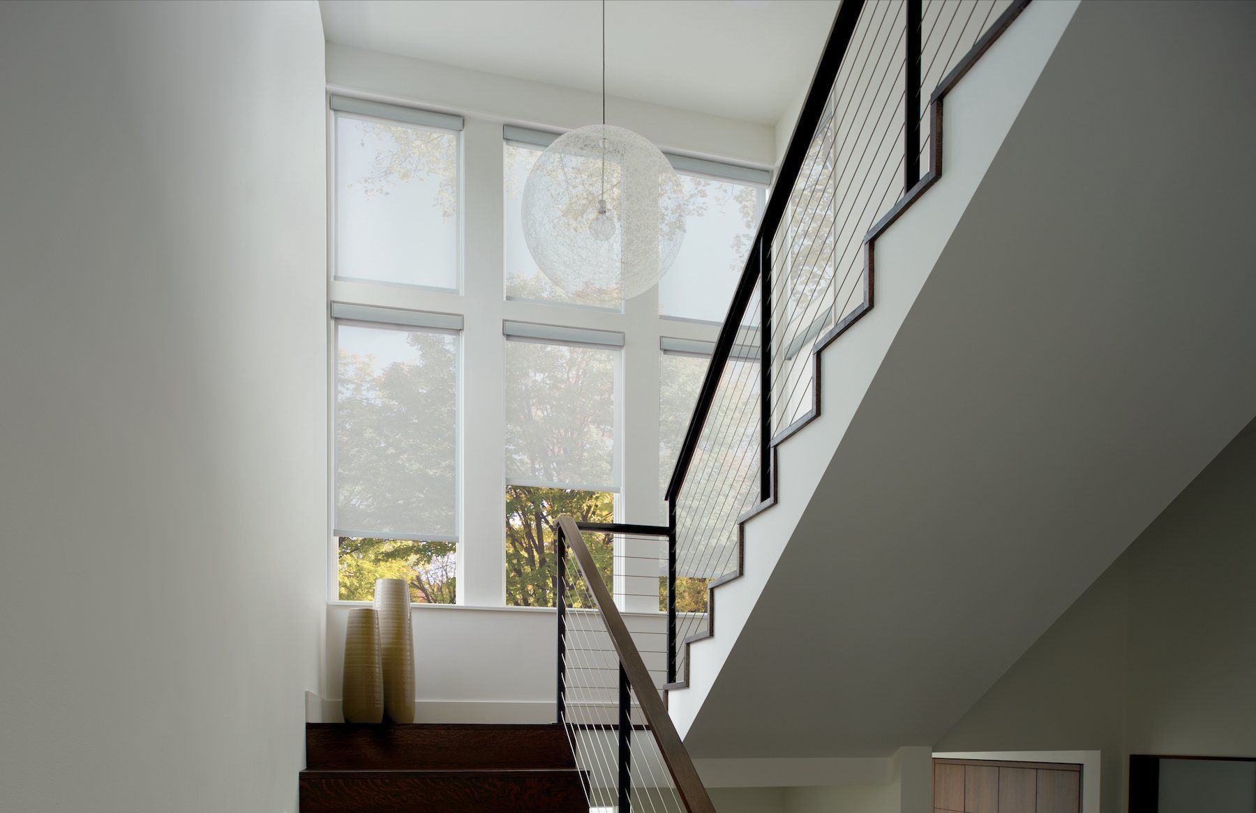 Staircase beside tall windows with a hanging pendant light in a bright modern interior
