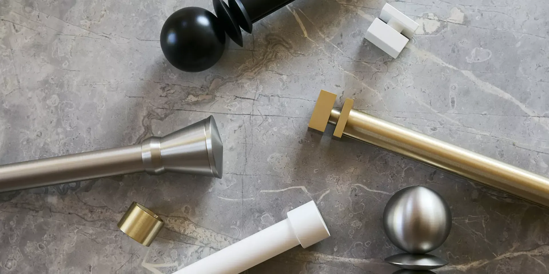 Assorted metal and plastic drawer knobs and pulls scattered on a gray surface
