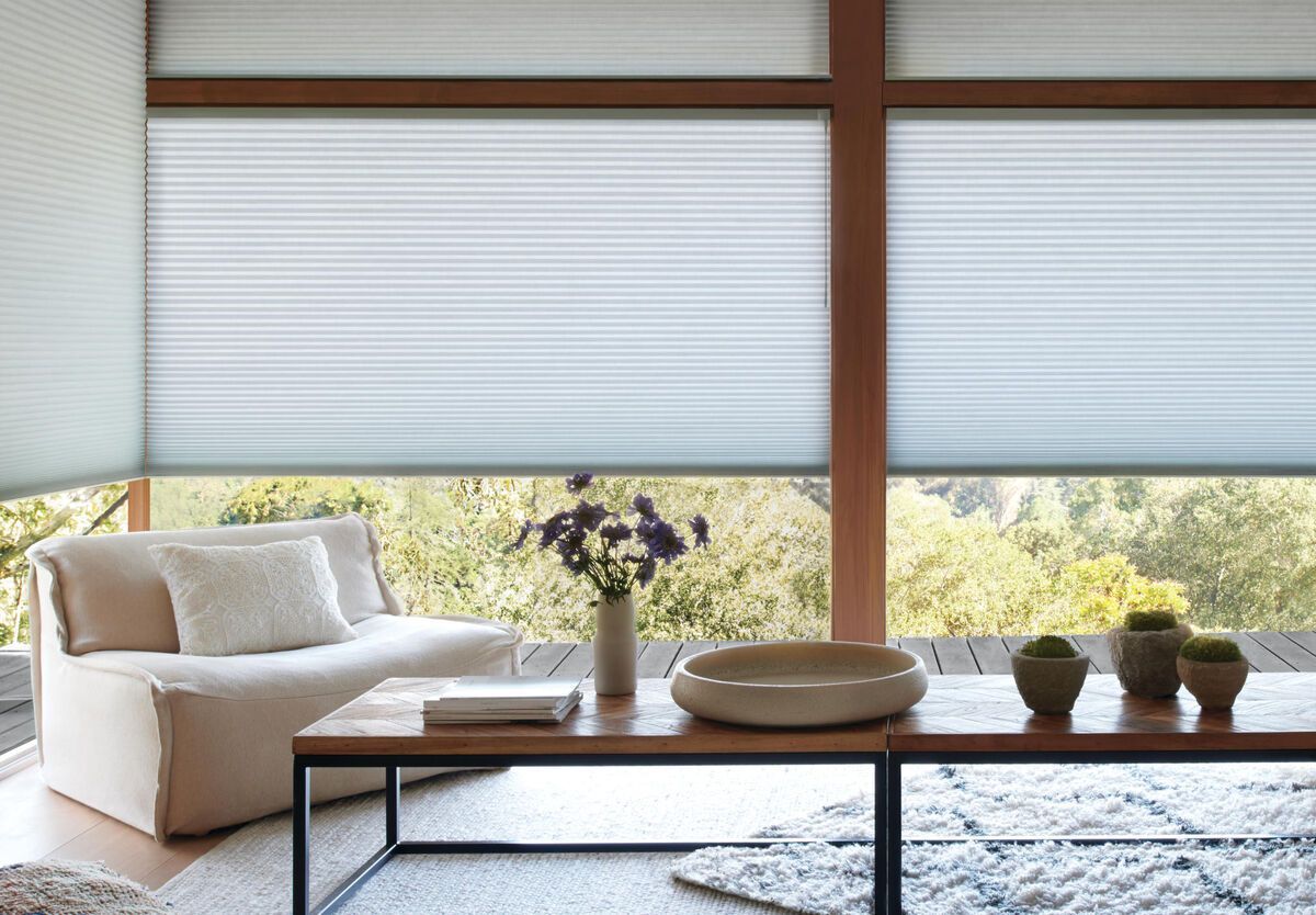 Minimalist living room with sofa, low table, floor cushions, and large windows with blinds