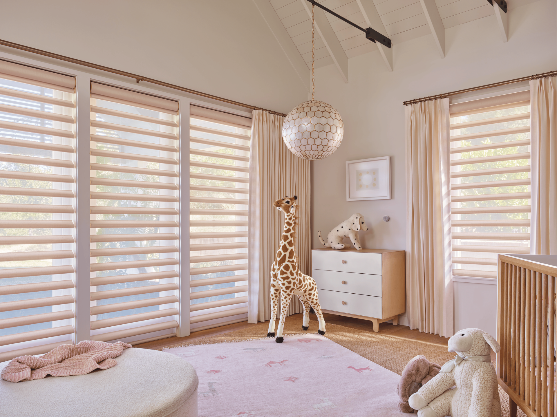 Bright nursery with white crib, giraffe toy, plush bunny, and beige curtains in a sunlit room
