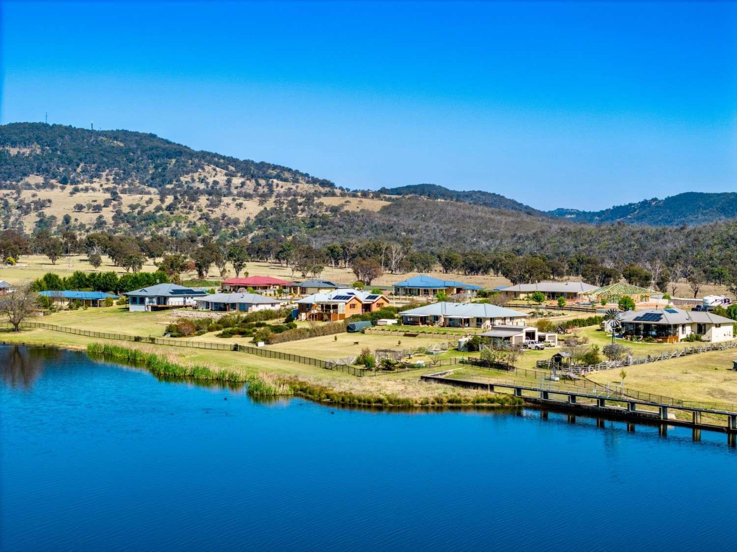 Houses Line a Lake with A Wooden Bridge — Walsh Demolition Pty Ltd in Tenterfield, NSW