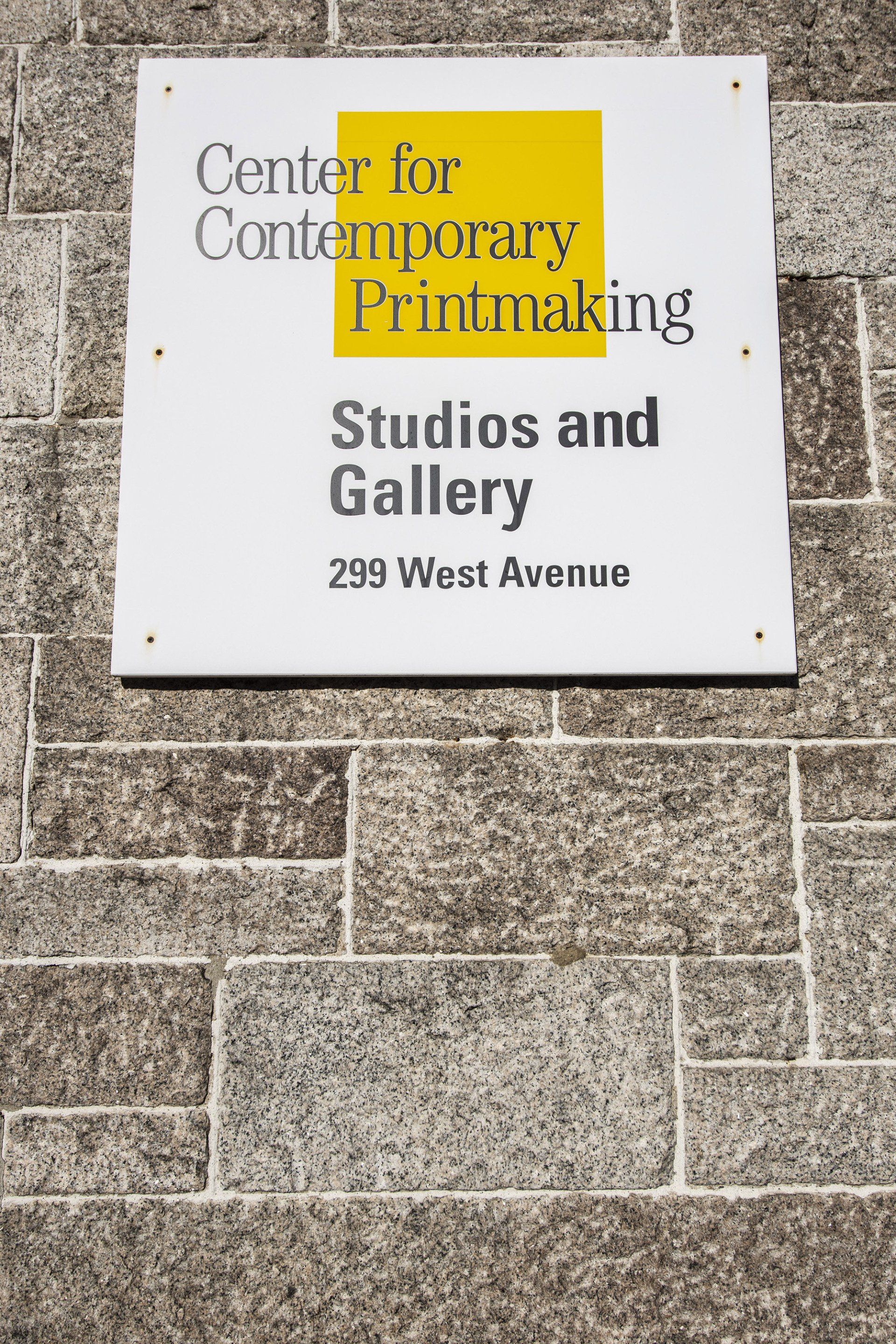 A white square sign on a stone wall reads: Center for Contemporary Printmaking, Studios and Gallery, 299 West Avenue.