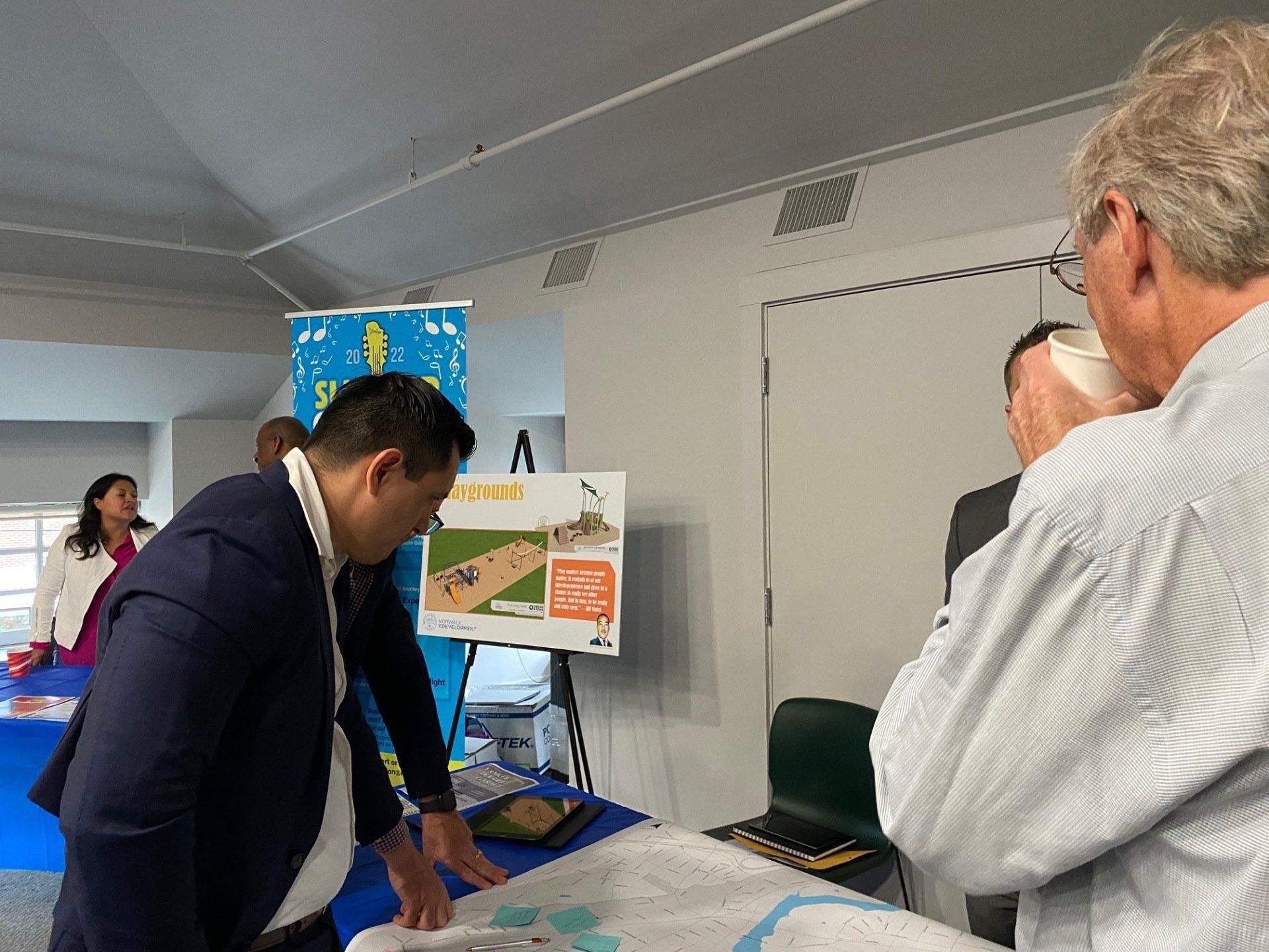 People discuss plans and maps at an indoor community or professional consultation event.
