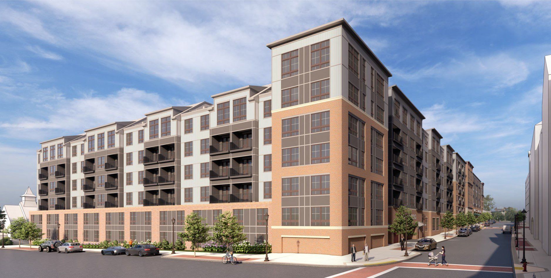 A modern multi-story apartment building with tan brick and gray siding, featuring balconies on a street corner.