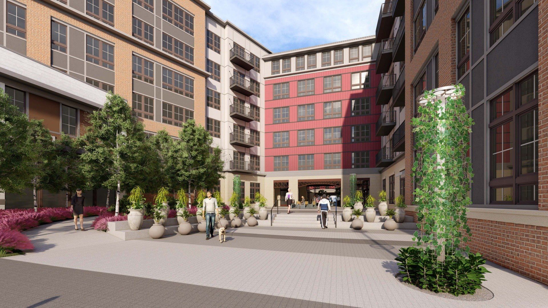 A courtyard between multi-story apartment buildings with potted plants, trees, and people walking on a paved walkway.