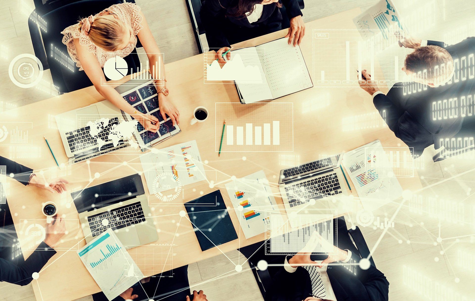 Overhead view of a business team at a conference table with digital data charts and network graphics overlaid.