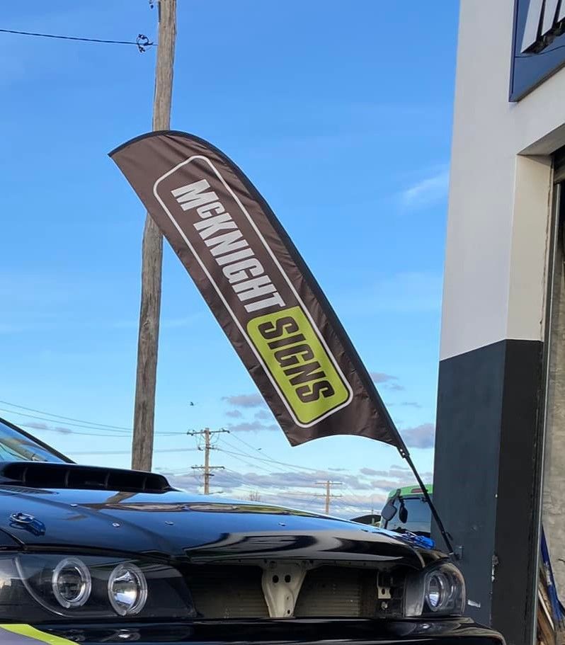 A Black Car is Parked in Front of a Mcknight Signs Flag — McKnight Signs In Armidale, NSW