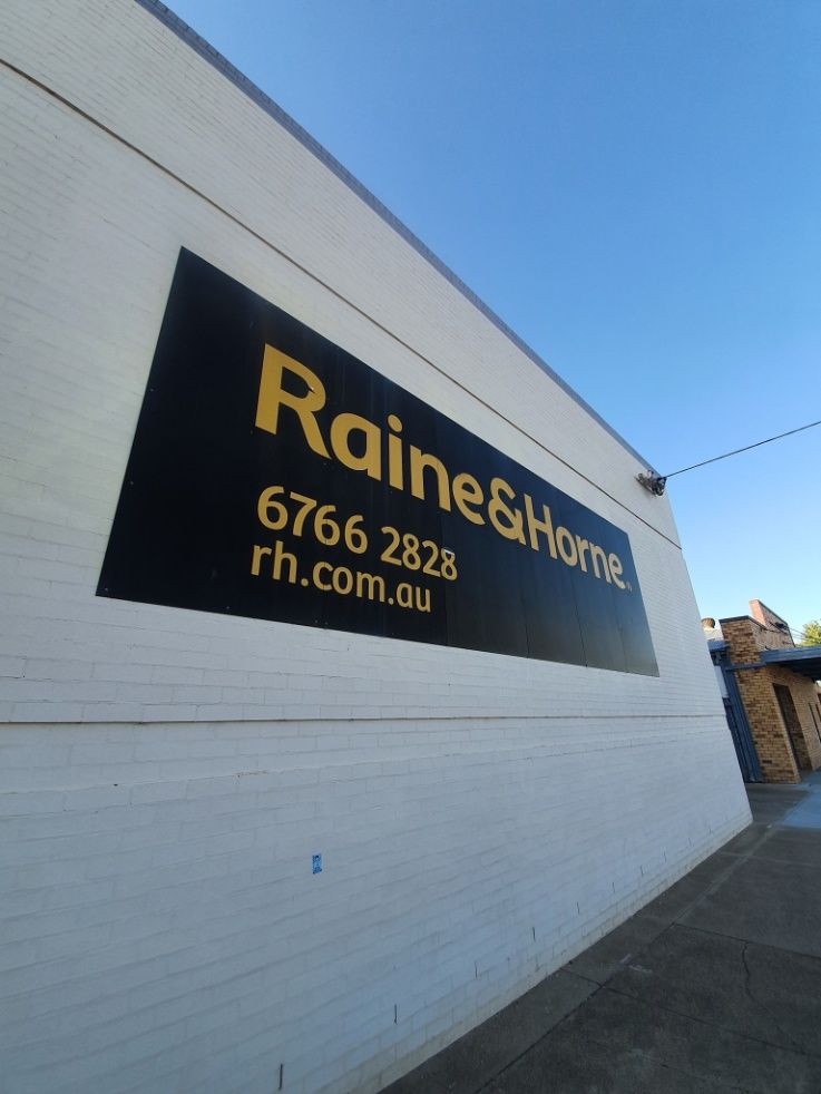 A Sign On The Side Of A Building That Says Raine & Home — McKnight Signs In Hillvue, NSW