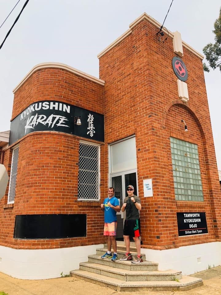 Two Men Are Standing In Front Of A Brick Building — McKnight Signs In Hillvue, NSW