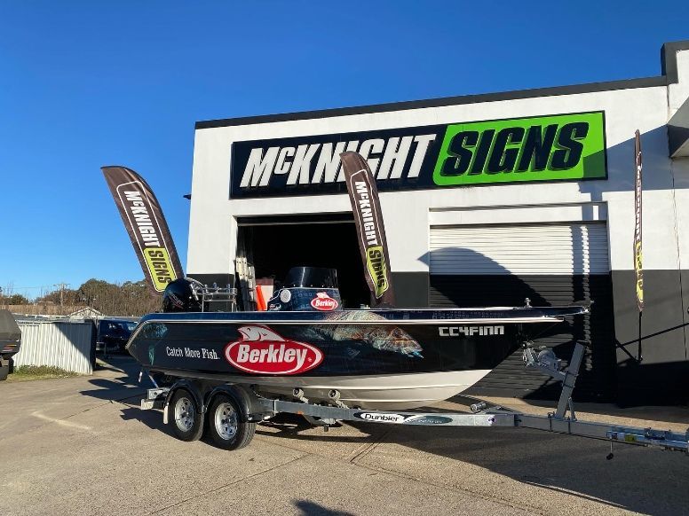 A Boat Is Parked In Front Of A Building That Says Mcknight Signs — McKnight Signs In Armidale, NSW