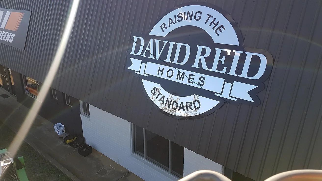 A Building With A Sign That Says Raising The David Reid Homes Standard — McKnight Signs In Armidale, NSW