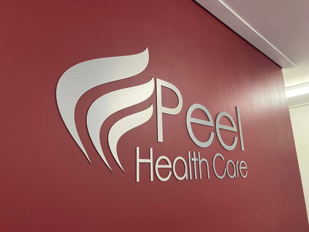 The Logo For Peel Health Care Is On A Red Wall — McKnight Signs In Armidale, NSW