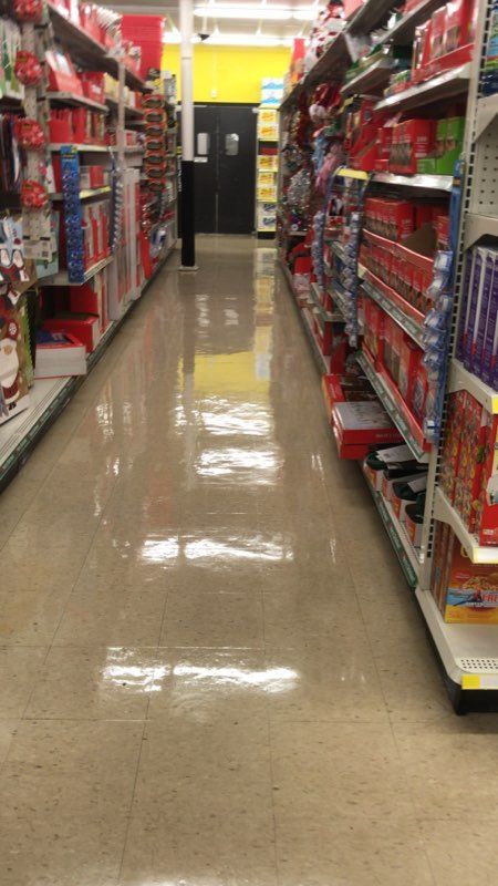 Grocery store aisle lined with shelves of red items, shiny floor, fluorescent lighting.
