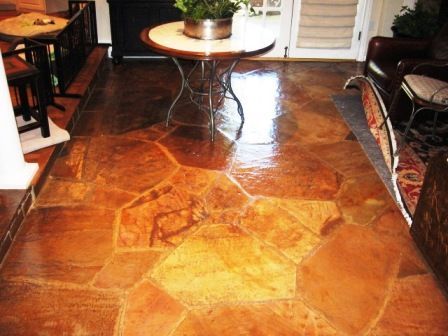 Brown, glossy stone floor with an organic, multi-shaped pattern. A table with a plant sits on it.