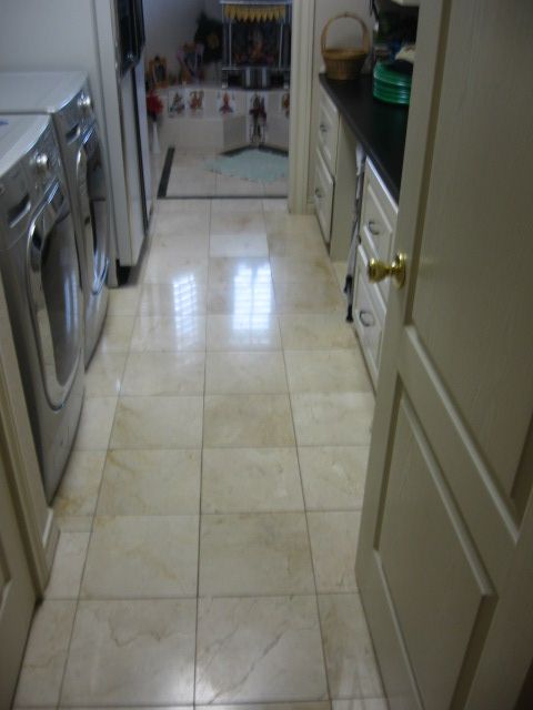 Hallway with beige tile floor leading to a kitchen. Washer and dryer are on the left.