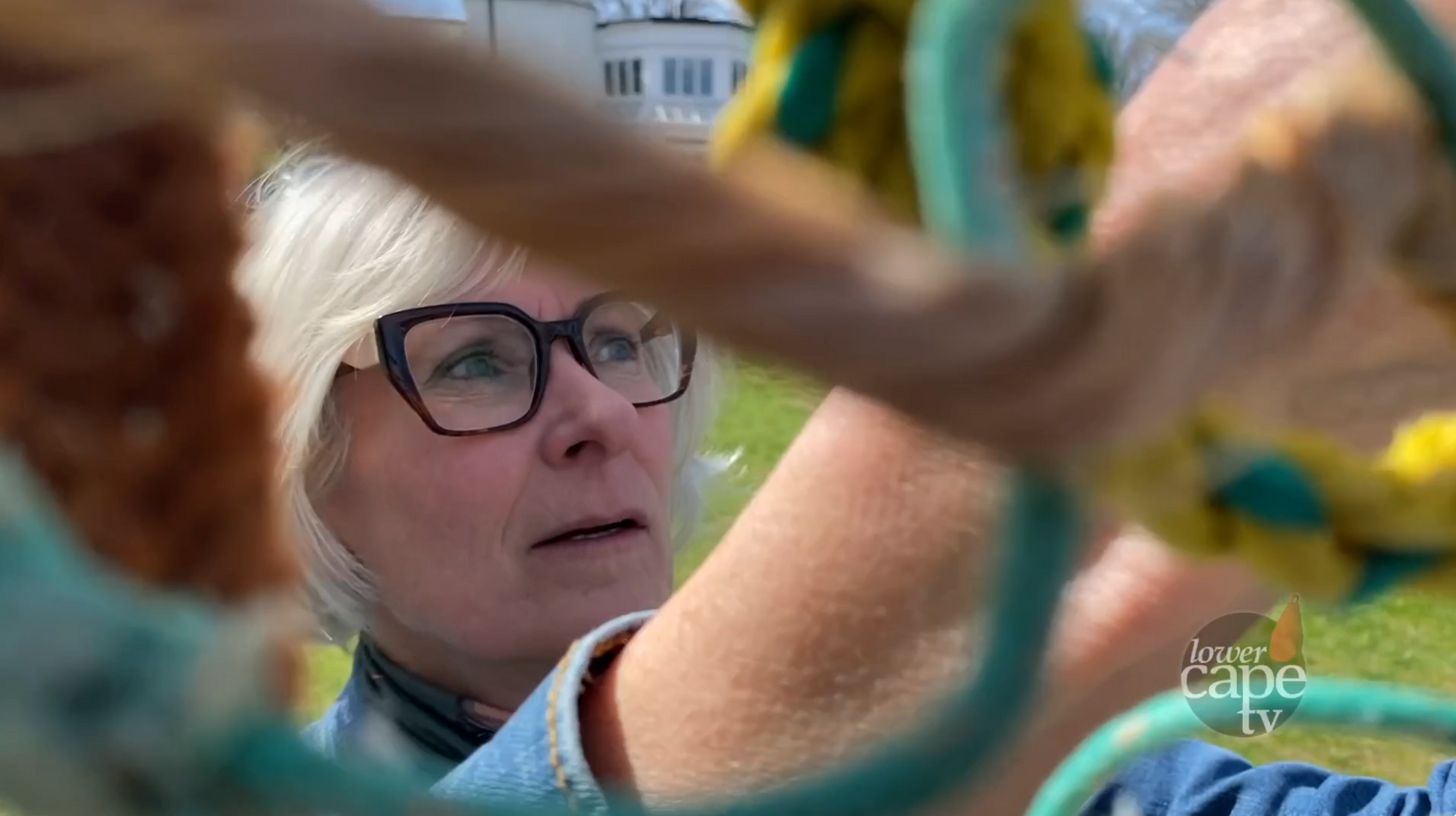 JoAnn Del Negro, blonde with glasses, weaves ropes of beach debris in an art installation.