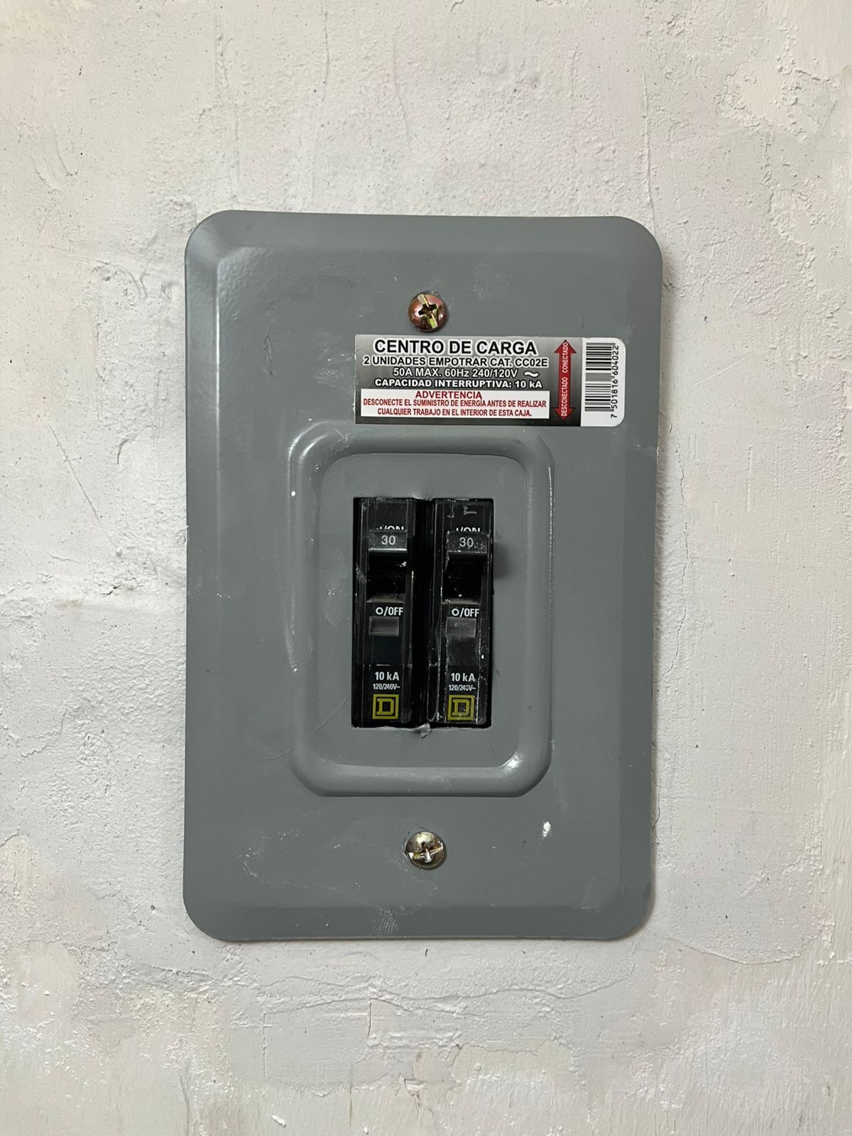 Un interruptor disyuntor eléctrico bipolar montado en una pared gris texturizada.