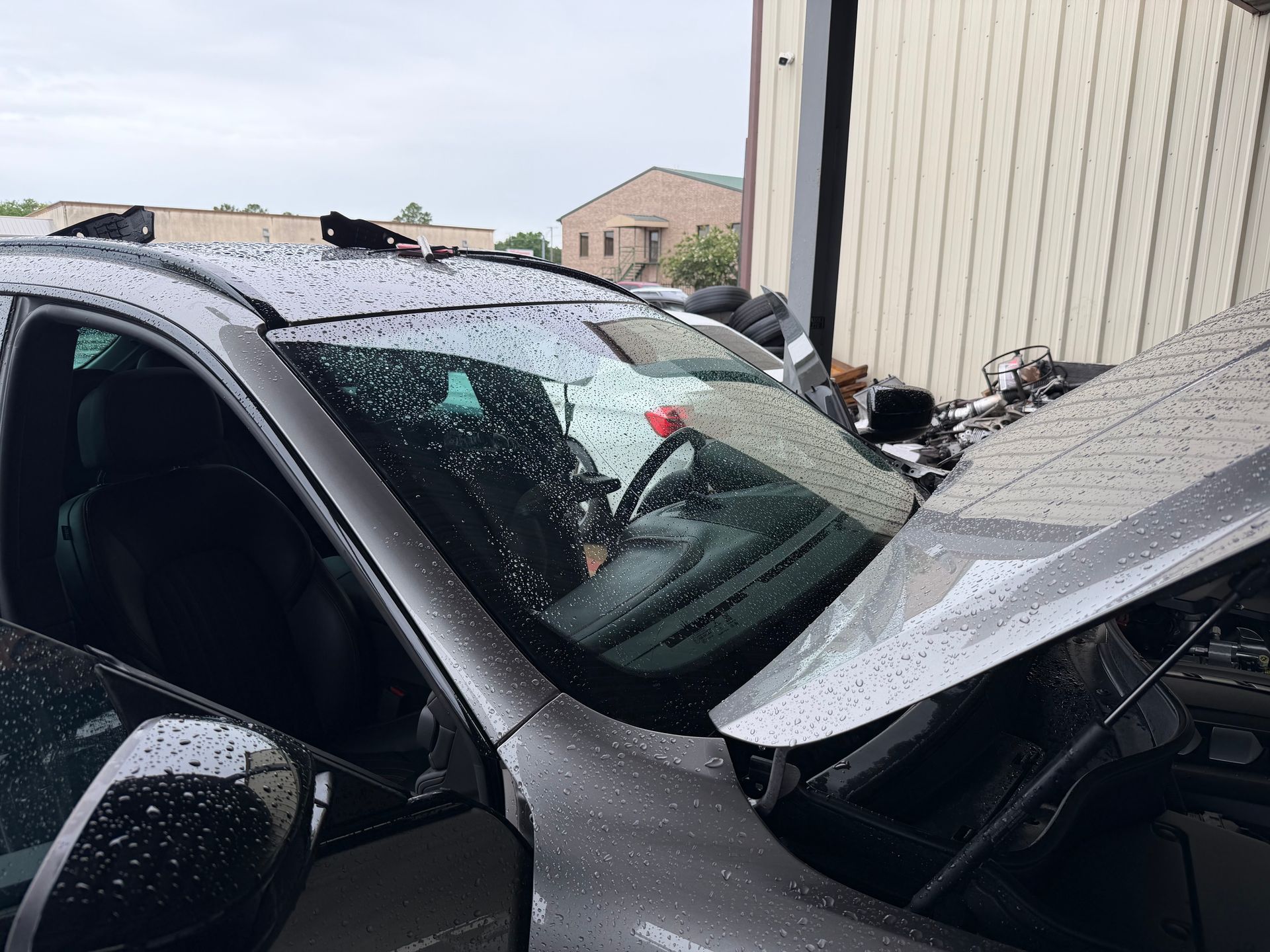 Damaged gray car with crumpled hood and shattered windshield after a collision by a building