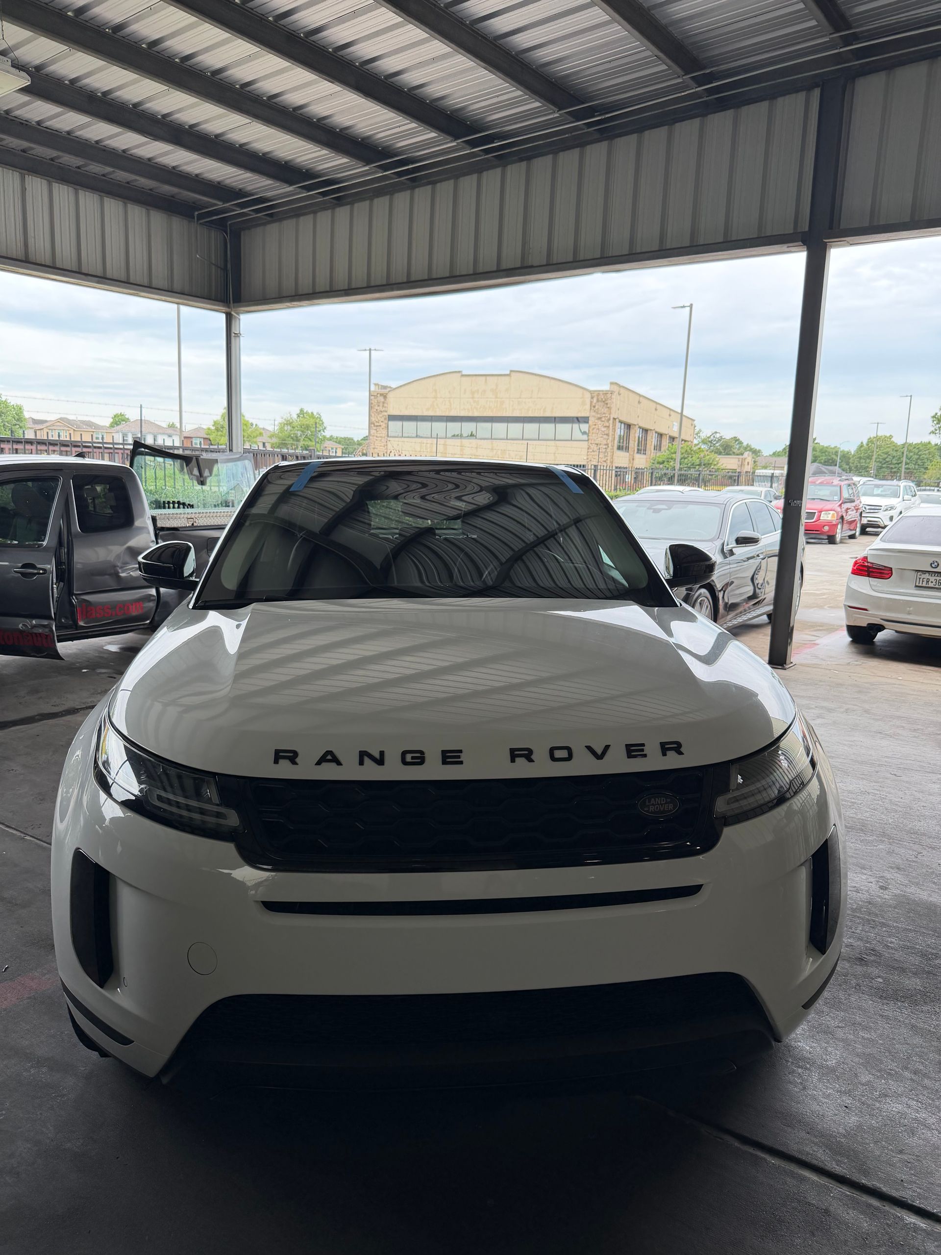 White Range Rover SUV parked under a covered lot, front view