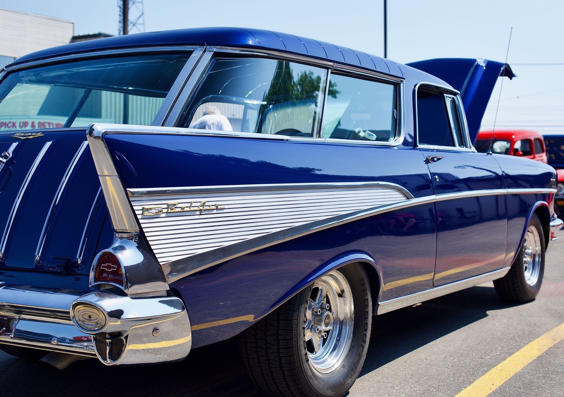 Classic dark blue vintage car parked outdoors, shown from the rear side with chrome details and fins.