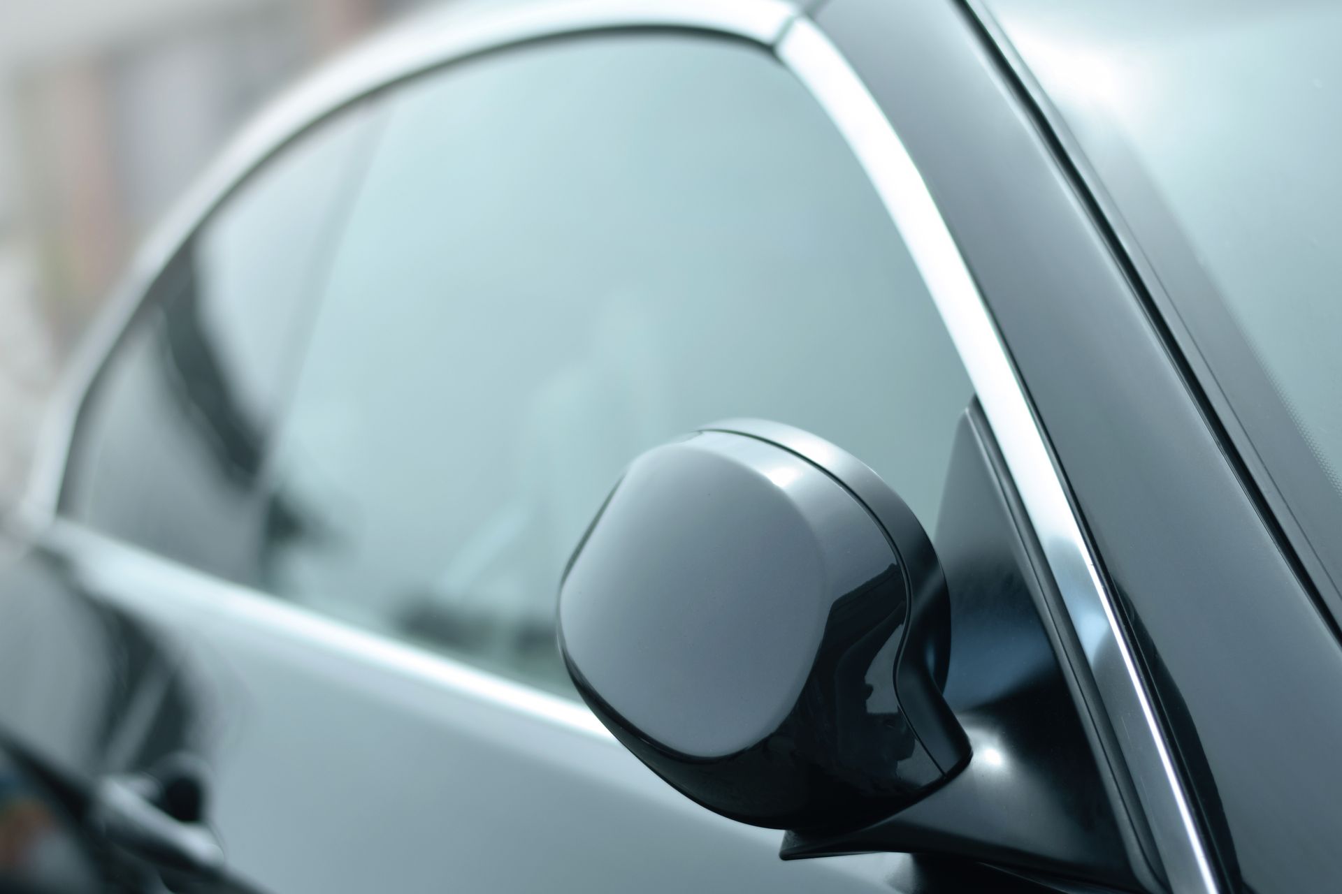 Close-up of a black car side mirror on a silver vehicle.