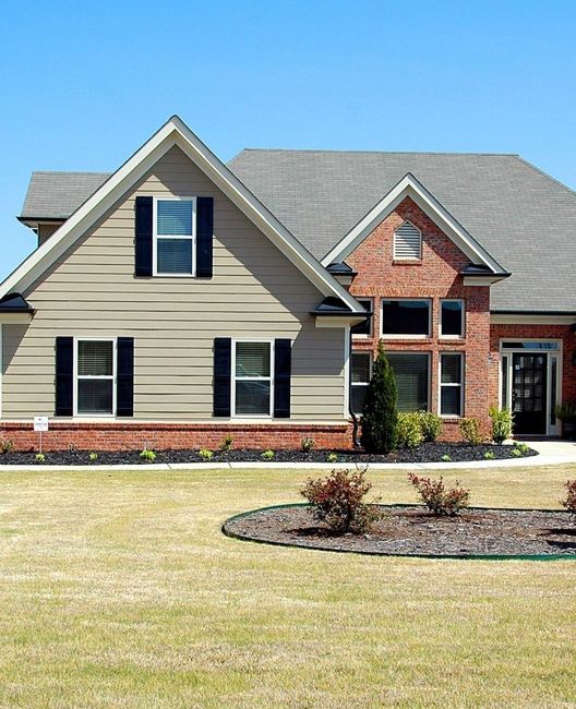 a brick house with a tan siding and black shutters