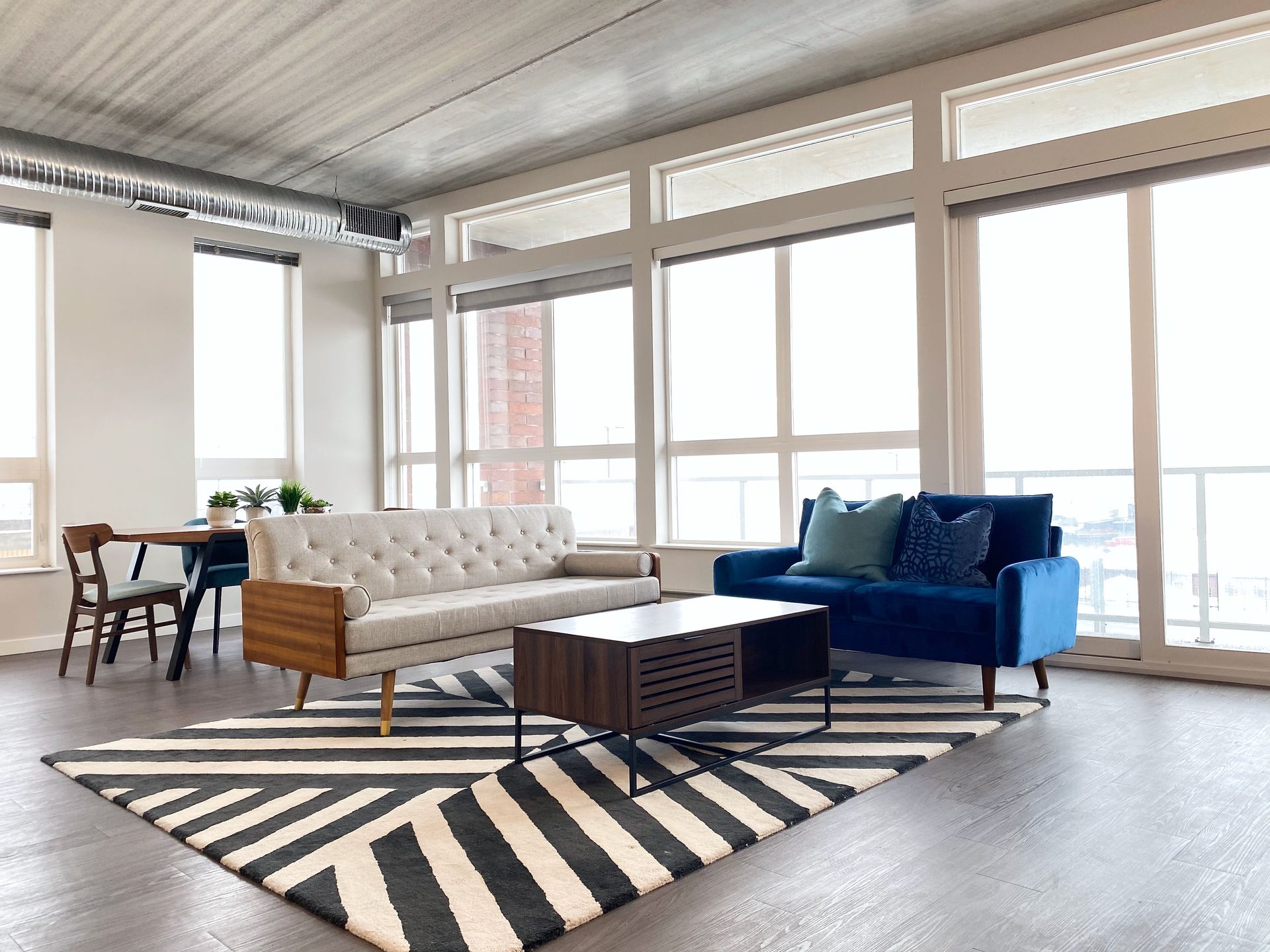 A living room with a couch , two chairs , a coffee table and a rug.