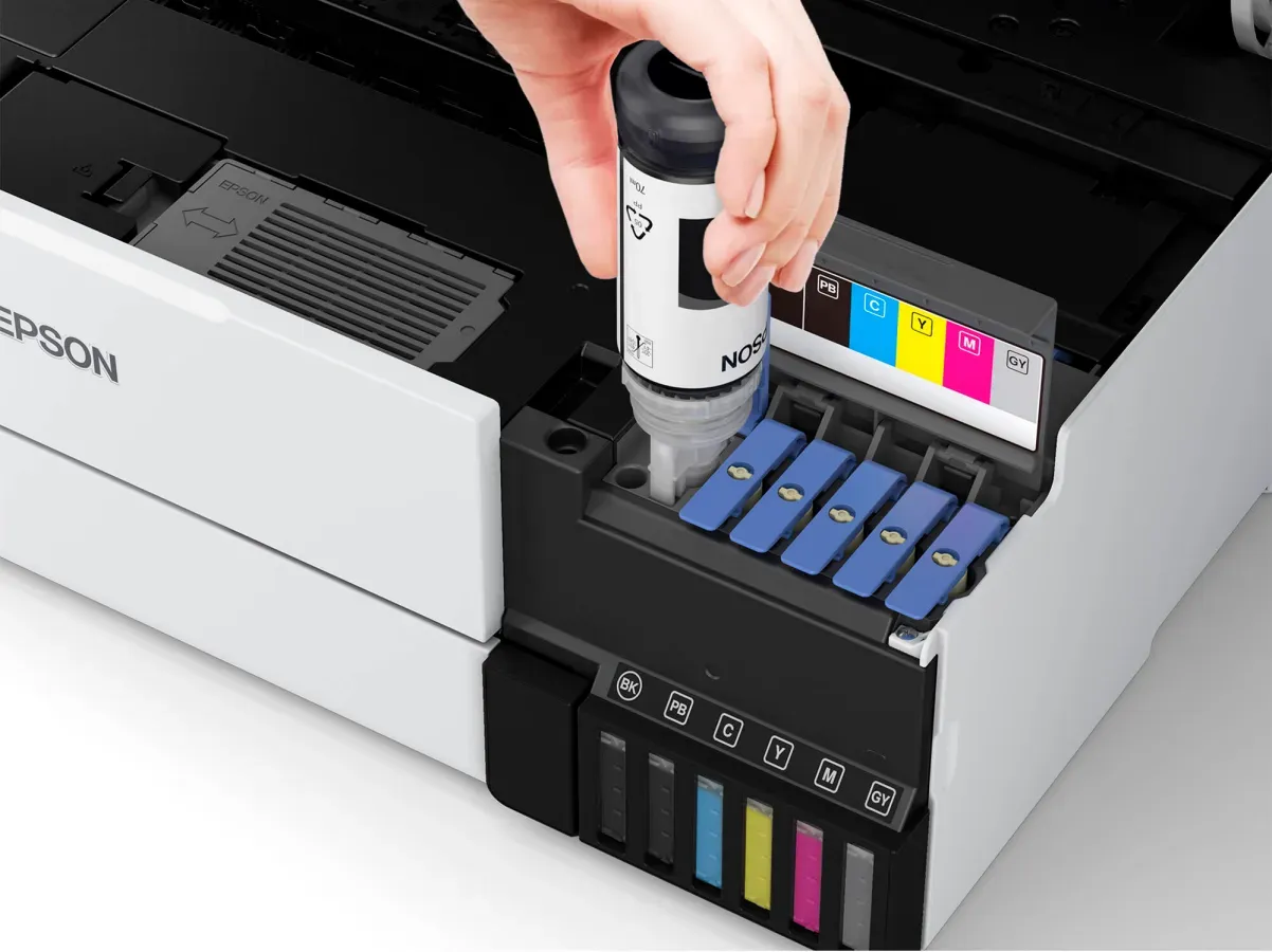 A person is pouring ink into an epson printer.