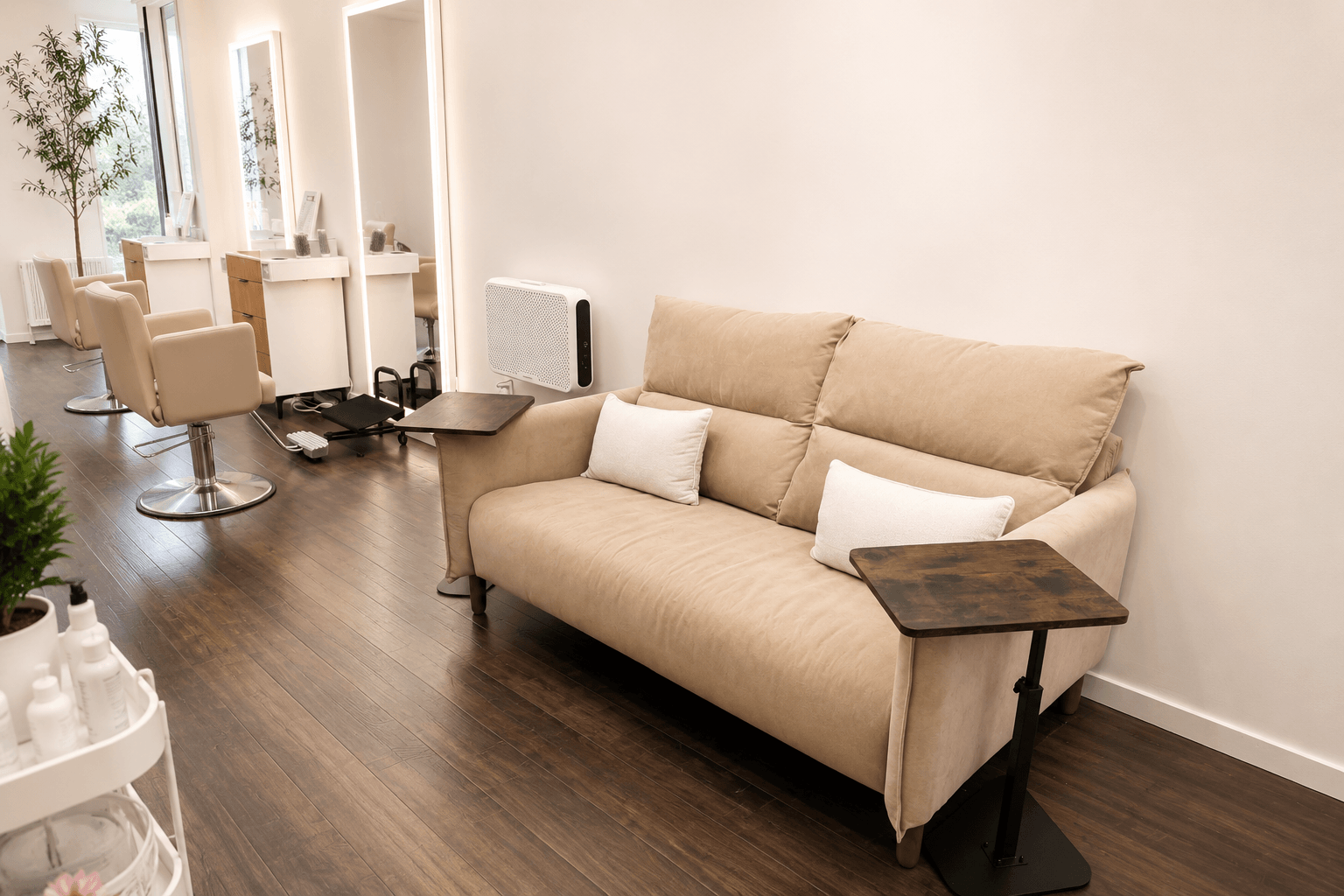 Bright living room with beige sofa, dark wood floor, and a salon chair near a vanity mirror