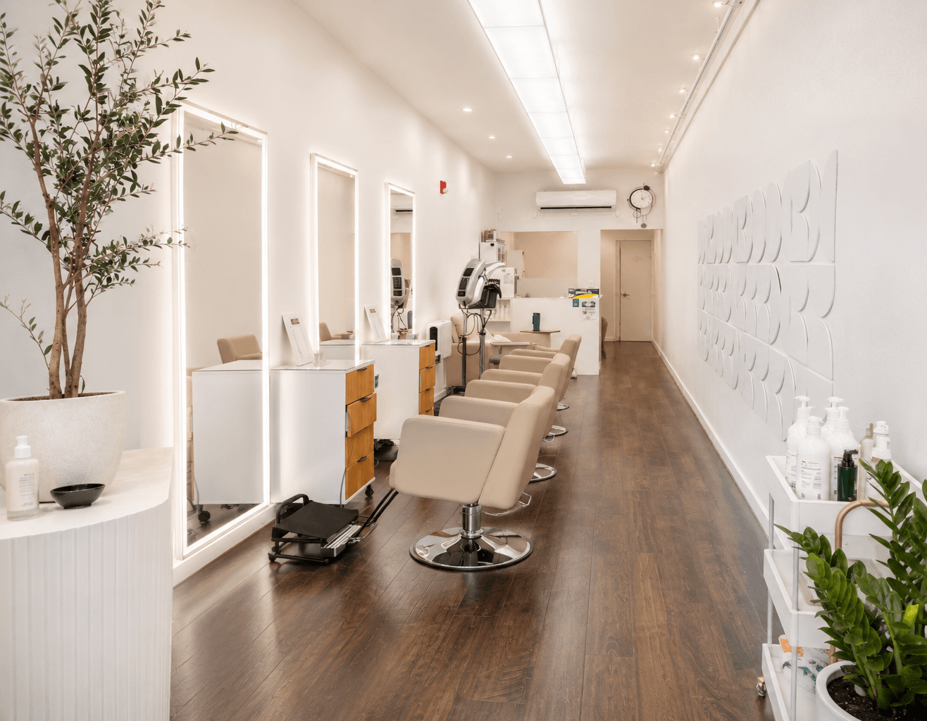 Modern salon interior with styling chairs, mirrors, wood floors, and white decor