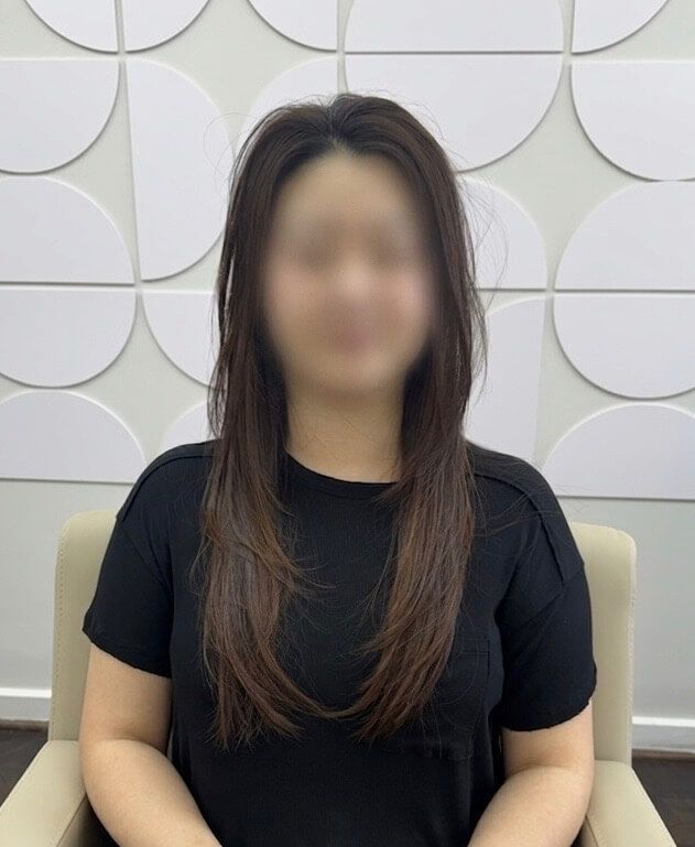 Seated person in a black shirt against a white geometric wall backdrop