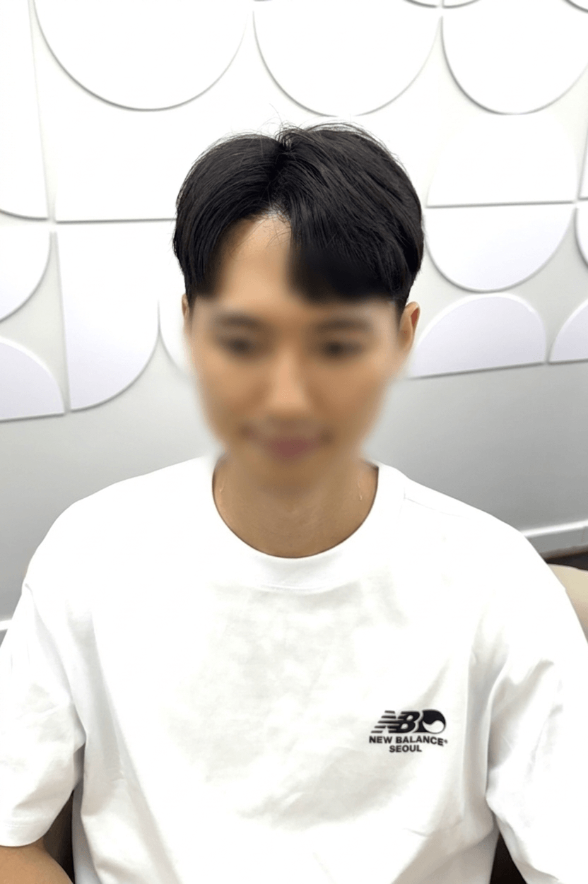 Person in a white shirt seated indoors against a light gray patterned wall.