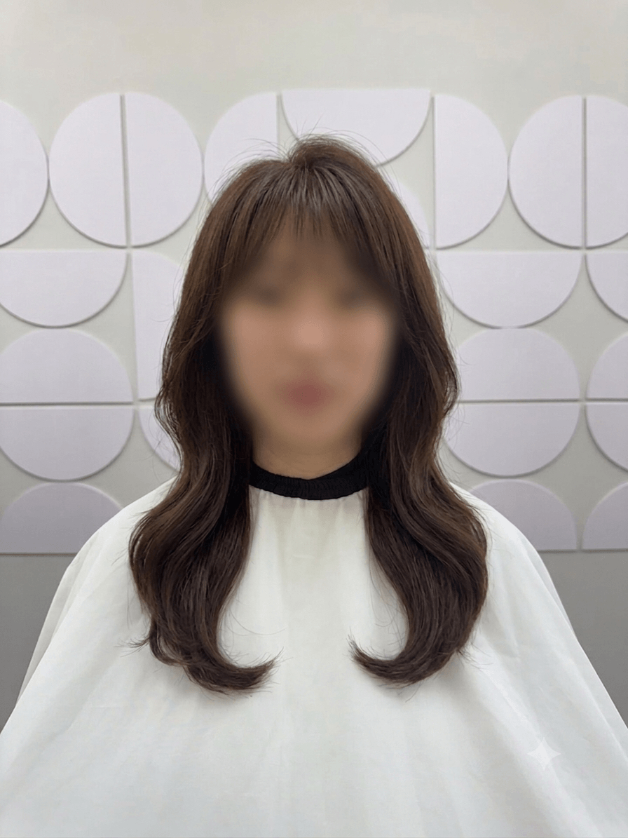 Person with long brown hair and white top standing before a wall of circular white panels