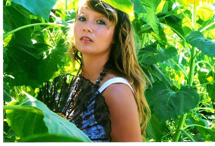 A woman is standing in a field of sunflowers