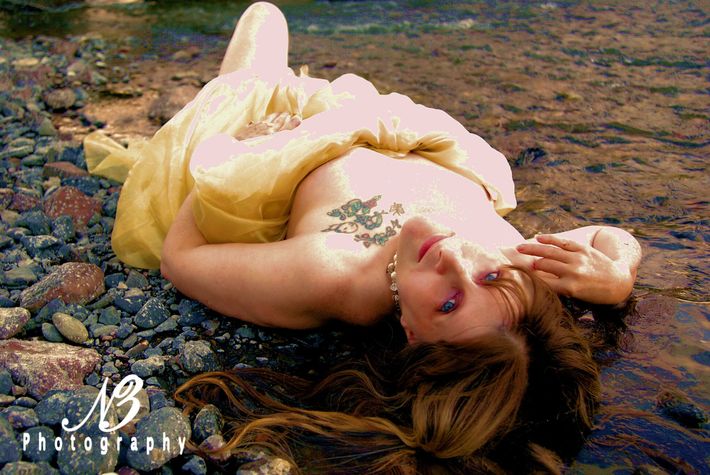 A woman in a yellow dress is laying in the water