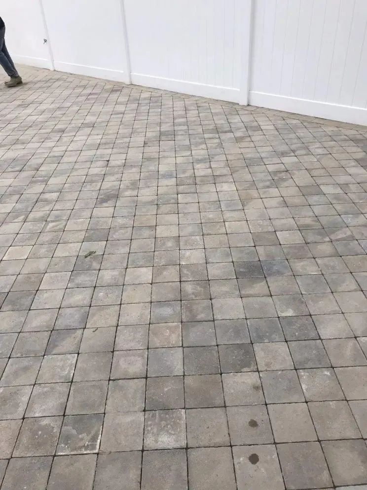 Gray stone paver patio beside a white fence, with a person partly visible at the left edge
