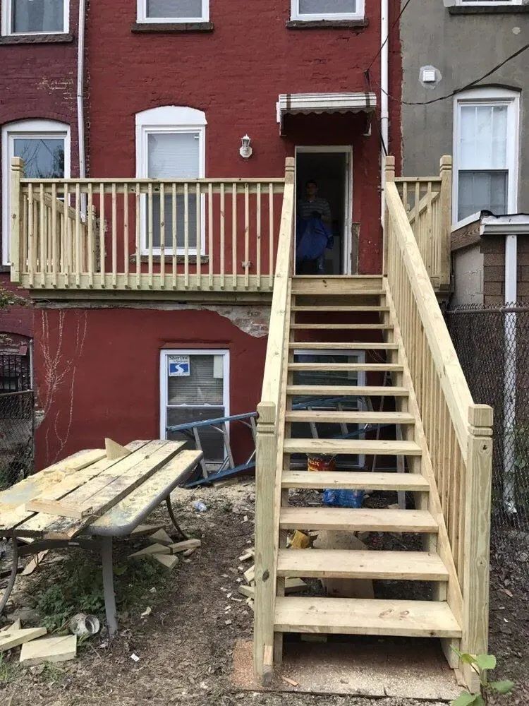 Wooden outdoor stairs leading to a red brick townhouse entrance under construction