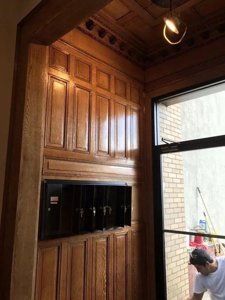 Wood-paneled interior with built-in shelves beside an open doorway; a person bends near the entrance.