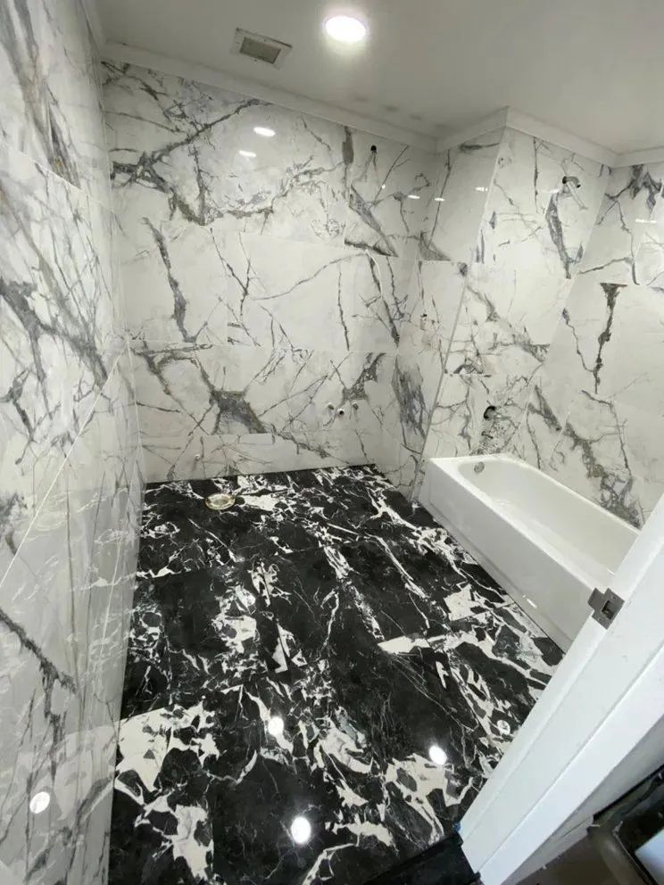 Marble-tiled bathroom with white walls, black floor, and a white bathtub.